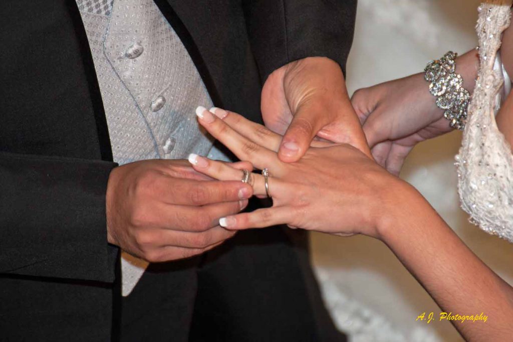 Groom placing ring on bride's finger